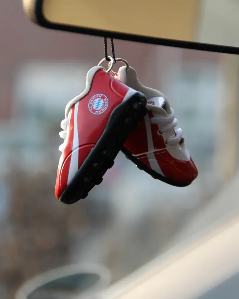Rot-weiße Mini-Fußballschuhe als Anhänger am Autorückspiegel