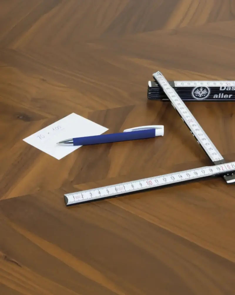 Zollstock mit Vereinswappen, Kugelschreiber und Notizzettel auf einem Holztisch