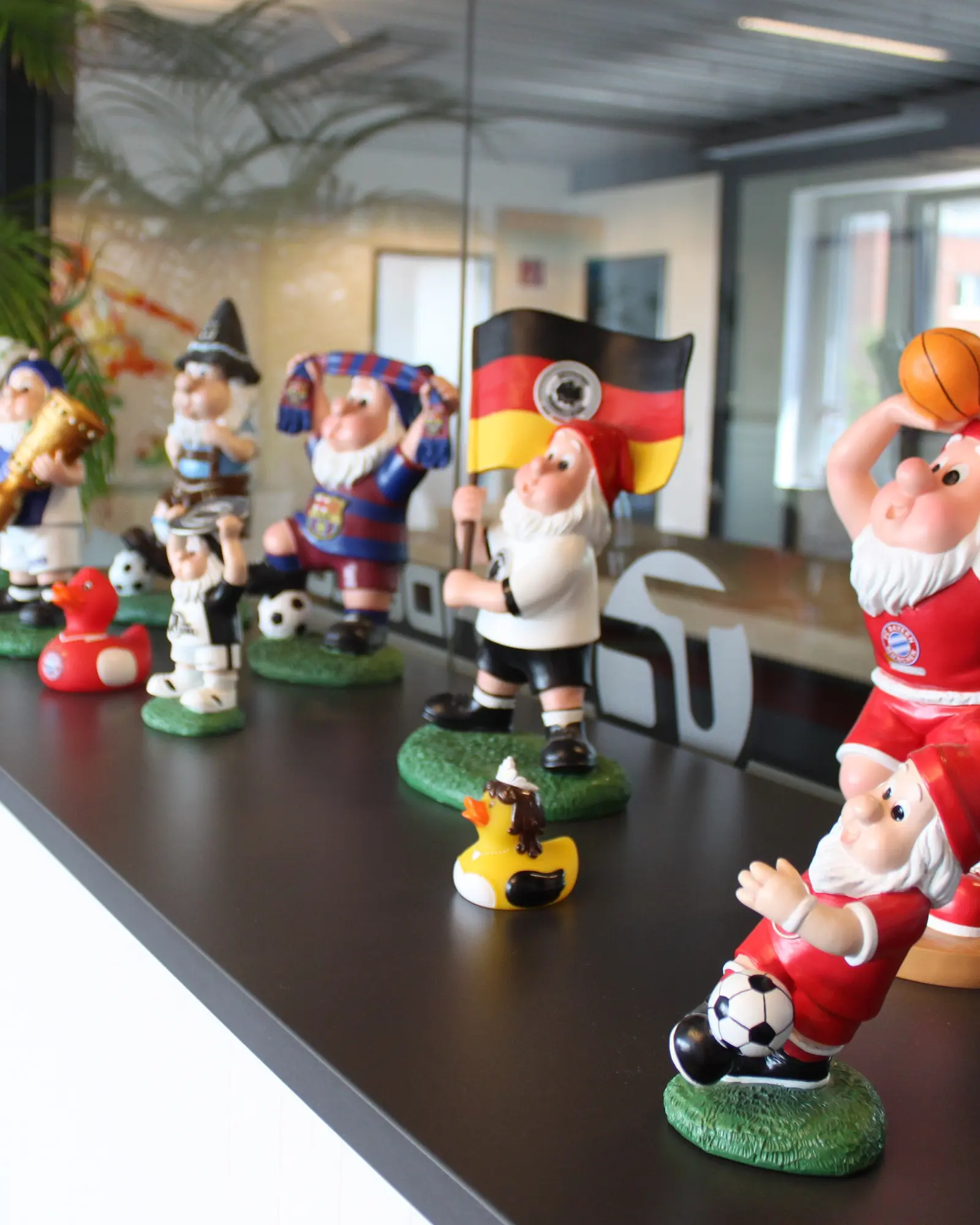 Fußball-Gartenzwerge und Badeenten in Vereinstrikots aufgereiht auf einem Regal